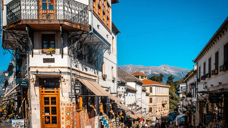 The old bazaar of Gjirokastër on a sunny day: old houses, souvenir shops and visitors in the street.