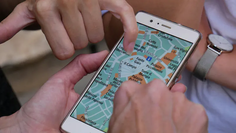 Dy duar zmadhojnë një hartë në ekranin e një telefoni.