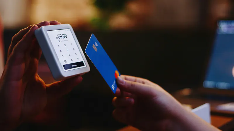 A bank card is held up to a contactless payment terminal.